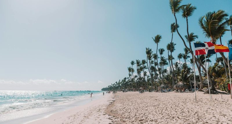 Domenican Republic visa guides Beautiful beach scene in Punta Cana, Dominican Republic, with clear skies and palm trees waving in the breeze.